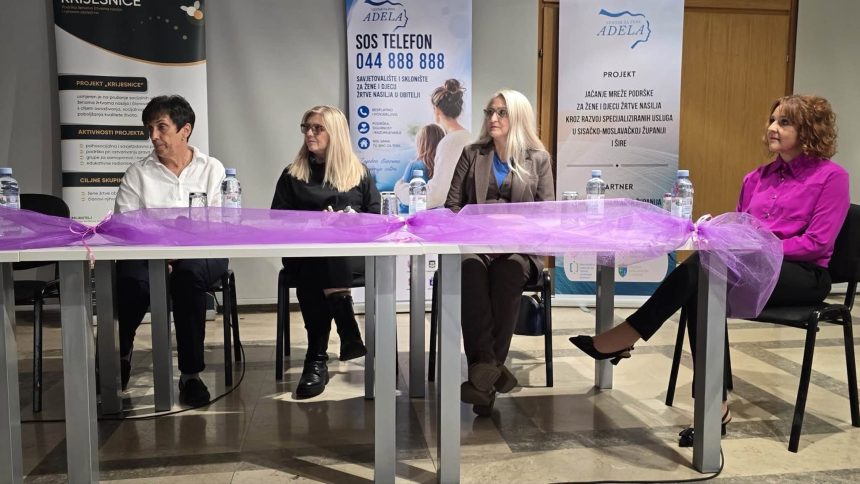 Četiri sudionice tribine za stolom ispred transparenata Centra za žene Adela.